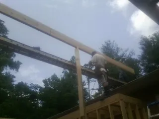 Carpenter setting a ridge beam over a new addition frame — Ice Dam Removal by Roofing Brothers in Riddle