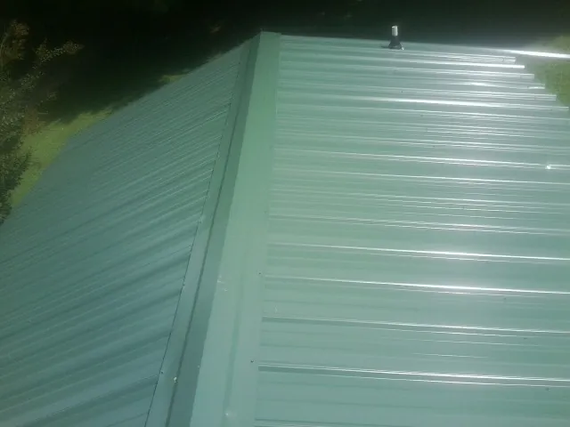 New green metal panels meeting at the ridge of a roof — Flat Roof Repair work by our crew in Riddle
