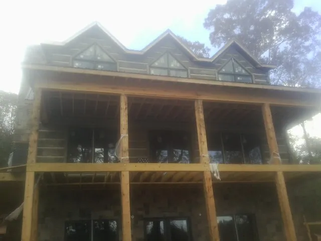 Dormers and porch framing on a large log home under construction — Roof Coating work by our crew in Riddle