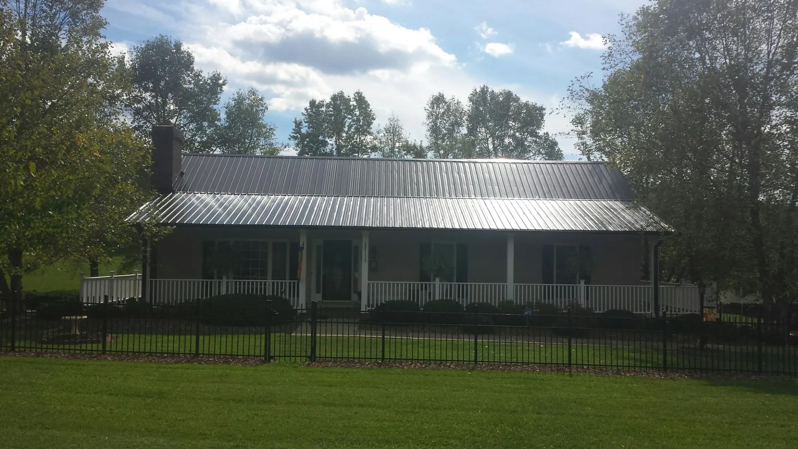 Gray metal roof on a brick ranch with a full width front porch — Gutter Guard Installation work by our crew in Riddle